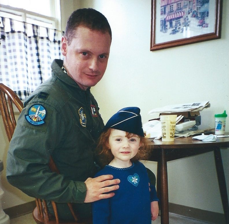 Photo of Lt. Col. Loftis with 2-year-old Alison wearing his Air Force cap