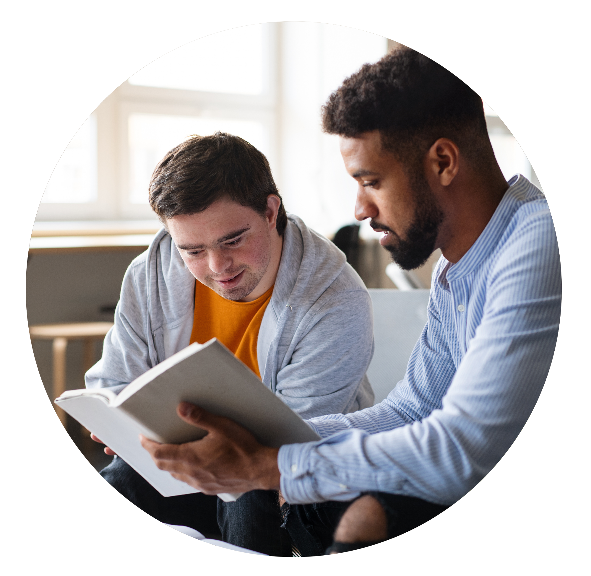 Young man reading to another young man in classroom